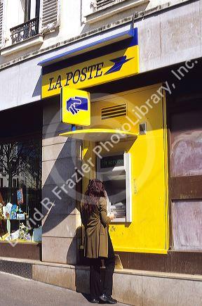 Woman using an atm machine at French Post Office.