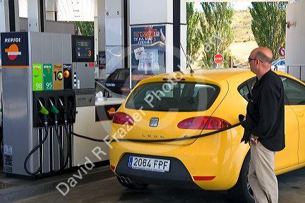 Customer putting fuel in his car at a gas station along the Autopisa near Pamplona, Navarre, northern Spain.