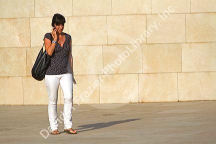 Woman talking on a cell phone in front of the Guggenheim Museum in the city of Bilbao, Biscay, Basque Country, northern Spain.