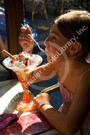 Young girl eating an ice cream sundae at a restaurant in the town of Saint-Jean-de-Luz, Pyrenees-Atlantiques, French Basque Country, Southwest France. MR