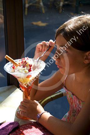 Young girl eating an ice cream sundae at a restaurant in the town of Saint-Jean-de-Luz, Pyrenees-Atlantiques, French Basque Country, Southwest France. MR