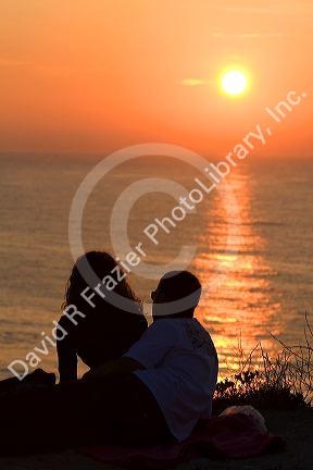 Couple watching the sunset over the Atlantic Ocean at Saint-Jean-de-Luz, Pyrenees Atlantiques, French Basque Country, Southwest France.