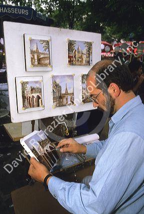 An artist paints and sells art at the Montmarte area of Paris, France.
