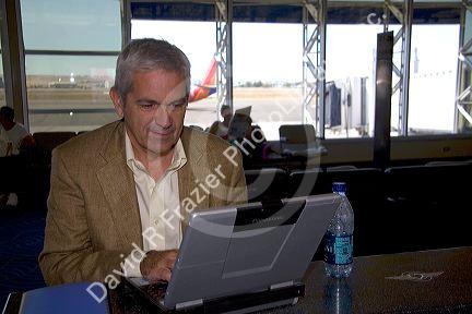 Man using a laptop computer in the Boise Airport, Boise, Idaho. MR
