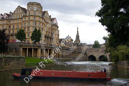 A narrowboat on the River Avon in front of the Pulteney Bridge and Abbey Hotel in the city of Bath, Somerset, England.