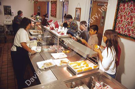 Multi ethnic school children wait in line for a school lunch.