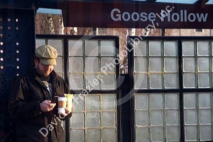 Passenger commuter using a cell phone at a MAX light rail stop in Portland, Oregon, USA.