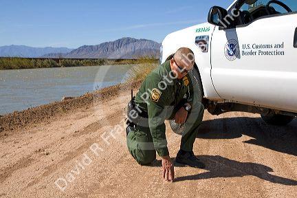 United States Border Patrol agent checking for footprints at the U.S./Mexico border along the All American Canal near Calexico, California.