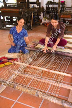 Vietnamese women weaving mats at a craft factory in Hoi An, Vietnam.