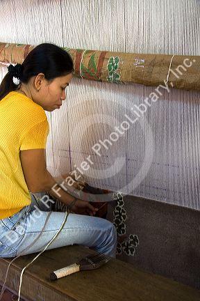 Vietnamese woman manufacturing woven rugs at a craft center in Hoi An, Vietnam.