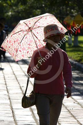 Vietnamese woman walking with an umbrella at the Imperial Citadel of Hue, Vietnam.