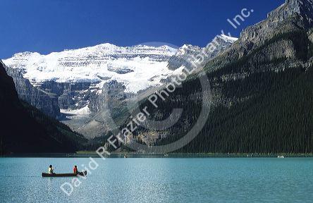 People canoeing on Lake Louise with a glacier in the background in Banff National Park, Canada.