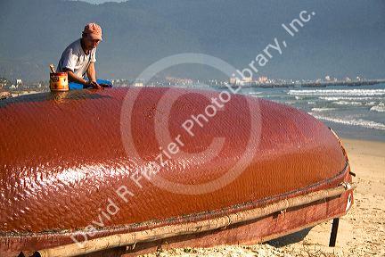 Vietnamese fisherman waterproofing the bottom of a woven fiber boat on China Beach near the port city of Da Nang, Vietnam.