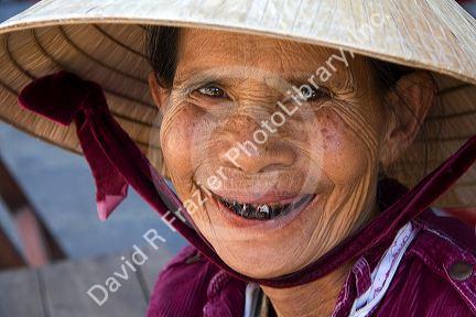 Portrait of an elderly Vietnamese woman whose teeth are stained from beetle nut wearing a tradional hat in Hoi An, Vietnam.