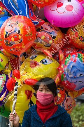 Street vendor selling colorful balloons for Tet in Hanoi, Vietnam.