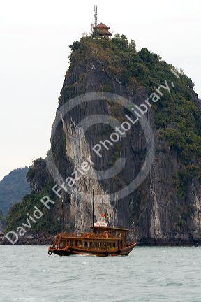 Limestone karast topped with an ancient structure and modern cell phone tower in Ha Long Bay, Vietnam.