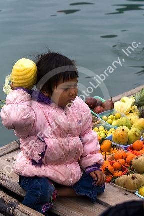 Vietnamese child on a boat selling fruit in Ha Long Bay, Vietnam.