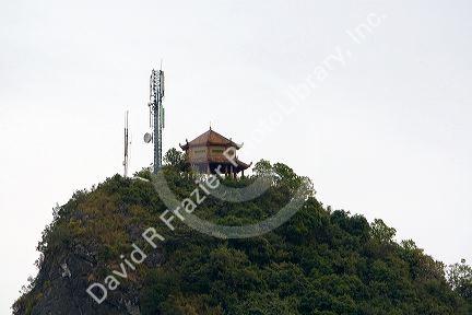 Limestone karast topped with an ancient structure and modern cell phone tower in Ha Long Bay, Vietnam.