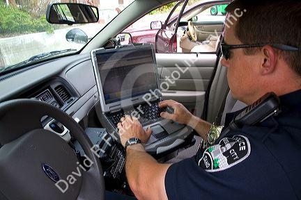 Police officer using a mobile data terminal computer inside a police car in Boise, Idaho, USA.