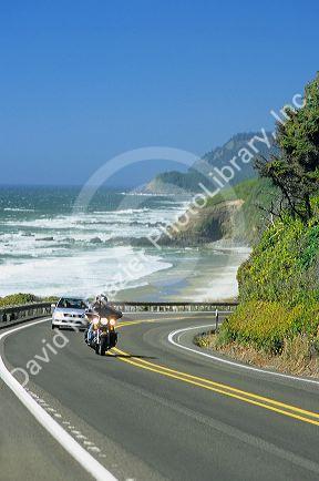 A motorcycle and car travel on U.S. Highway 101 along the oregon coast.