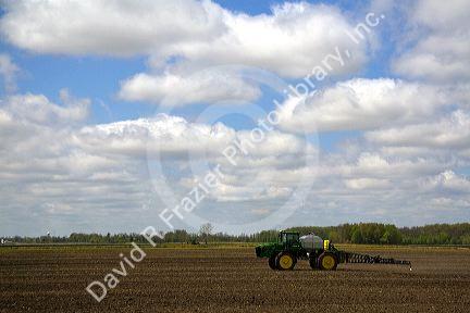 Tractor spraying herbicide on tilled crop soil in Lapeer County, Michigan, USA.