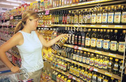 Woman shopping for olive oil in a grocery store.