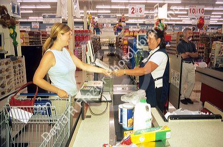 Customer and store clerk exchanging money for payment for groceries. (MR)