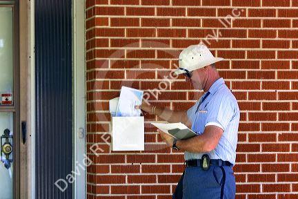 Postman delivering mail to a residence in Boise, Idaho, USA.