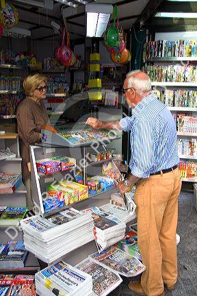 French man purchasing a newspaper from a Presse news kiosk in Sanary-sur-Mer, France.