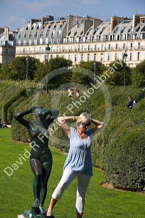 Visitor posing next to a statue at the Tuileries Garden near the Lourve in Paris, France.
