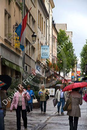 Pedestrians walk in the rain on a walking street in Luxembourg City, Luxembourg.
