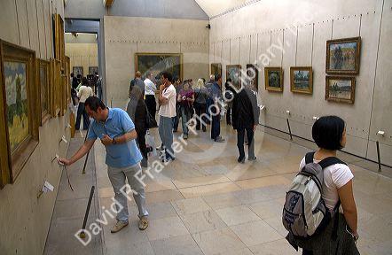 Visitors view artwork displayed in the Musee d'Orsay, Paris, France.