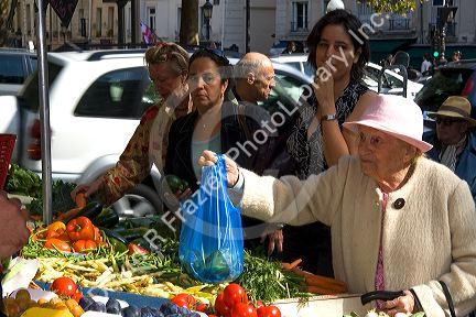 People shopping for produce at an outdoor Saturday market in Paris, France.