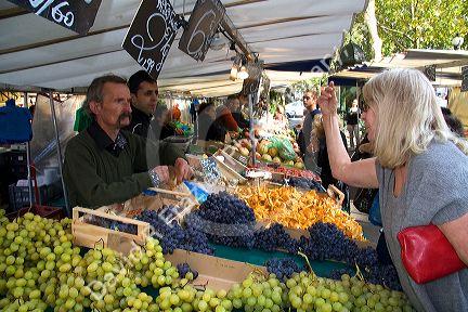 People shopping for produce at an outdoor Saturday market in Paris, France.