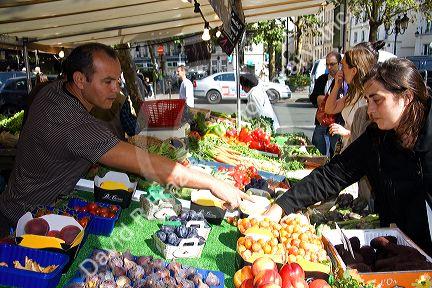 People shopping for produce at an outdoor Saturday market in Paris, France.
