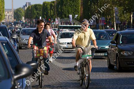 People ride bicycles along the Avenue des Champs-Elysees in Paris, France.