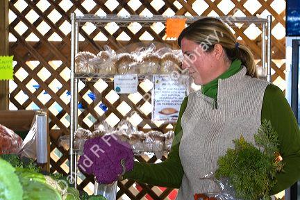 Woman shopping for purple cauliflower at a farmers market in Fruitland, Idaho. MR