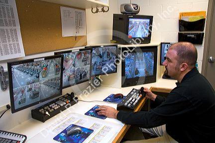 Security officer watching video monitors in the control room of a supermarket in, Idaho, USA.