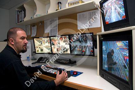 Security officer watching video monitors in the control room of a supermarket in, Idaho, USA.