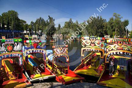 Colorful trajineras travel on the Xochimilco canals within Mexico City, Mexico.