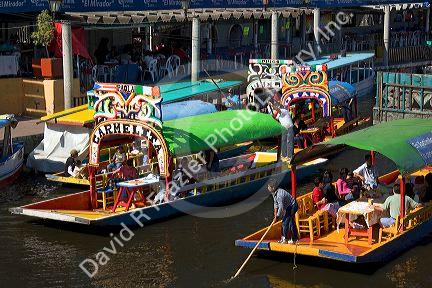 Colorful trajineras travel on the Xochimilco canals within Mexico City, Mexico.