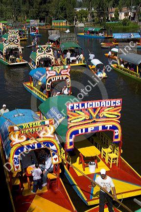 Colorful trajineras travel on the Xochimilco canals within Mexico City, Mexico.