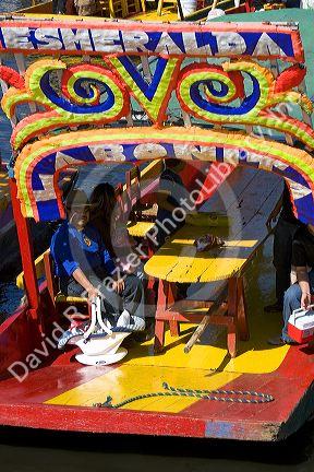 Colorful trajineras travel on the Xochimilco canals within Mexico City, Mexico.