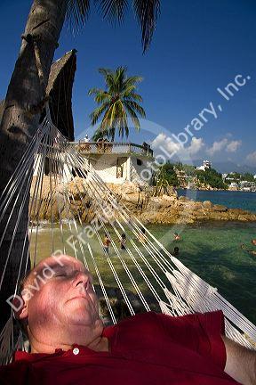 American tourist napping in a hammock on Island Roqueta, Acapulco, Guerrero, Mexico.