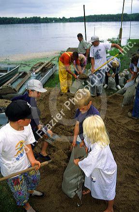 Adult and children volunteers fill sandbags for a flooded Mississippi River in Princeton, Iowa, USA.