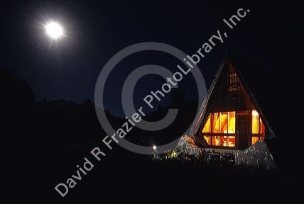 A-frame cabin lit up at night in the Andes mountain range in Chile.