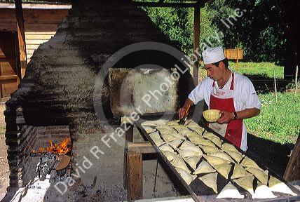 Chilean man cooking empanadas in a brick oven in Sanitiago, Chile.