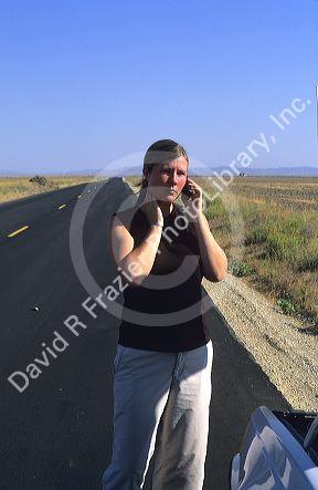 Stranded woman using a cell phone to call for help.