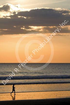 People walk on the beach at sunset in Jaco, Costa Rica.