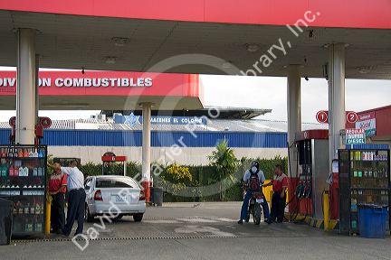 Attendants pump fuel at a gas station in Limon, Costa Rica.